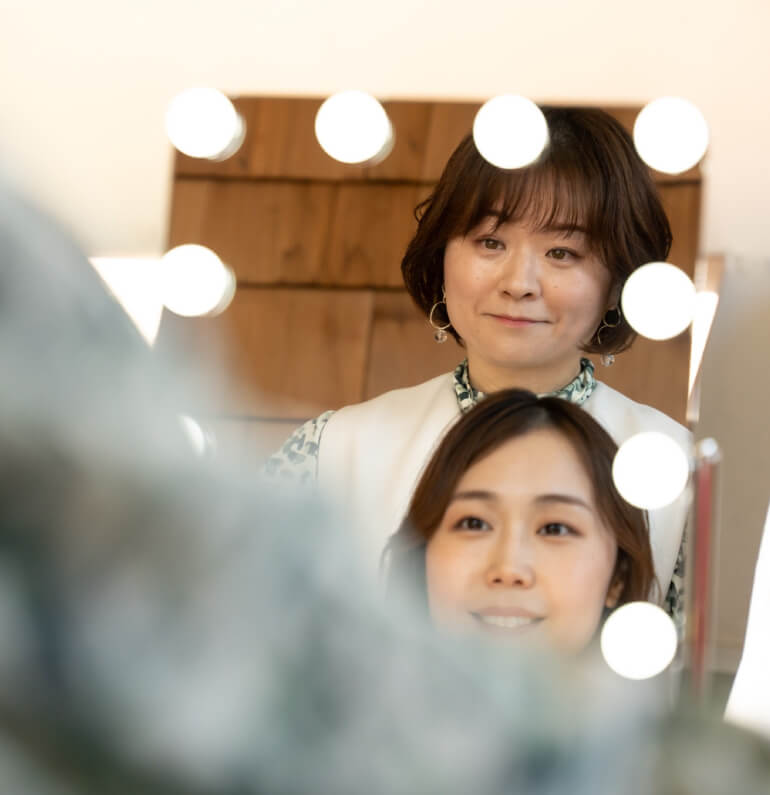 鏡を見てメイク方法をお伝えするオーナーとお客様